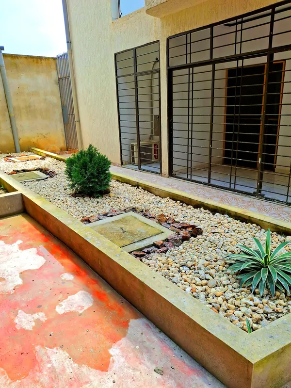 Jardinière et allée devant un immeuble neuf – Aménagement extérieur